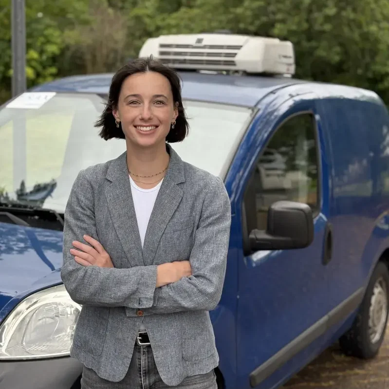 A Propos Elena devant sa voiture de livraison